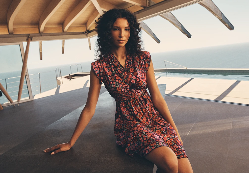 Model is wearing a Ruffle Floral Patchwork Mini Dress while sitting