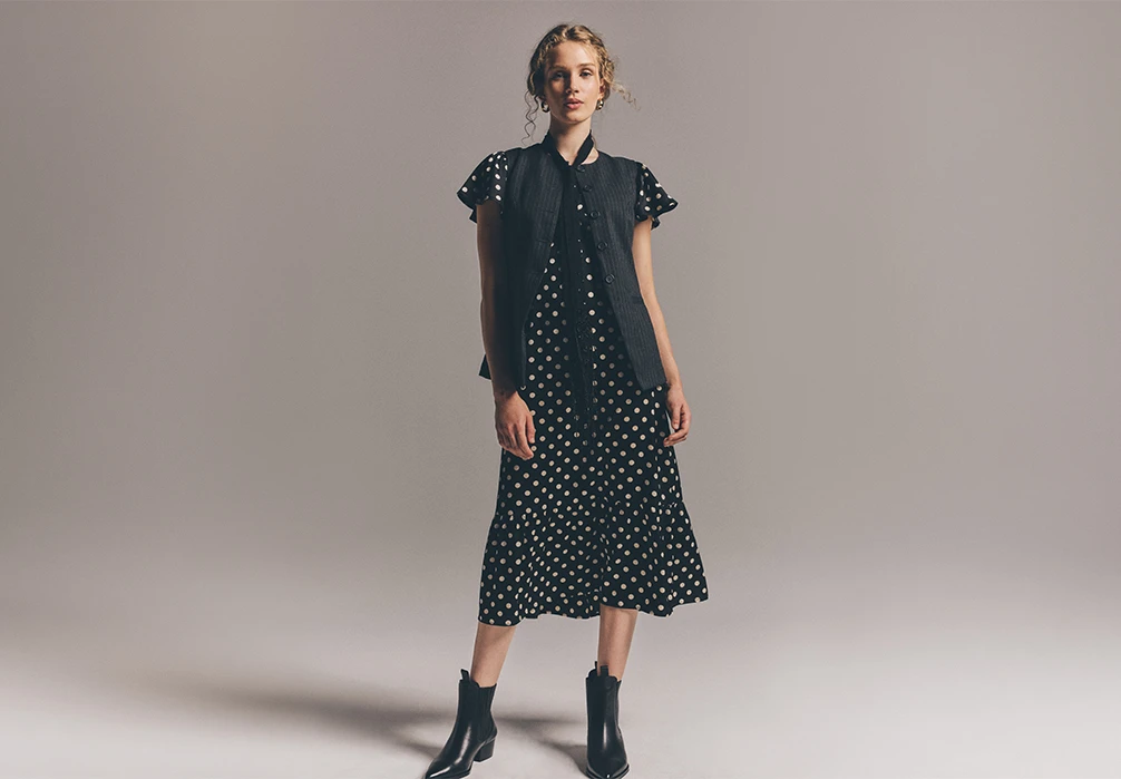 Model is wearing a black polka dot satin midi dress