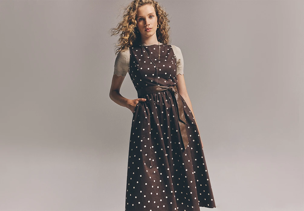 Model is wearing a brown A line polka dot midi dress