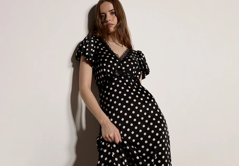 The model is wearing a black and white Polka Dot Satin Midi Dress