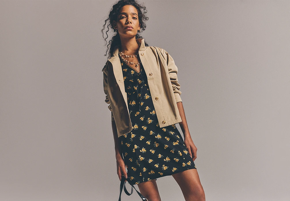 Model is standing wearing and black and yellow floral mini dress
