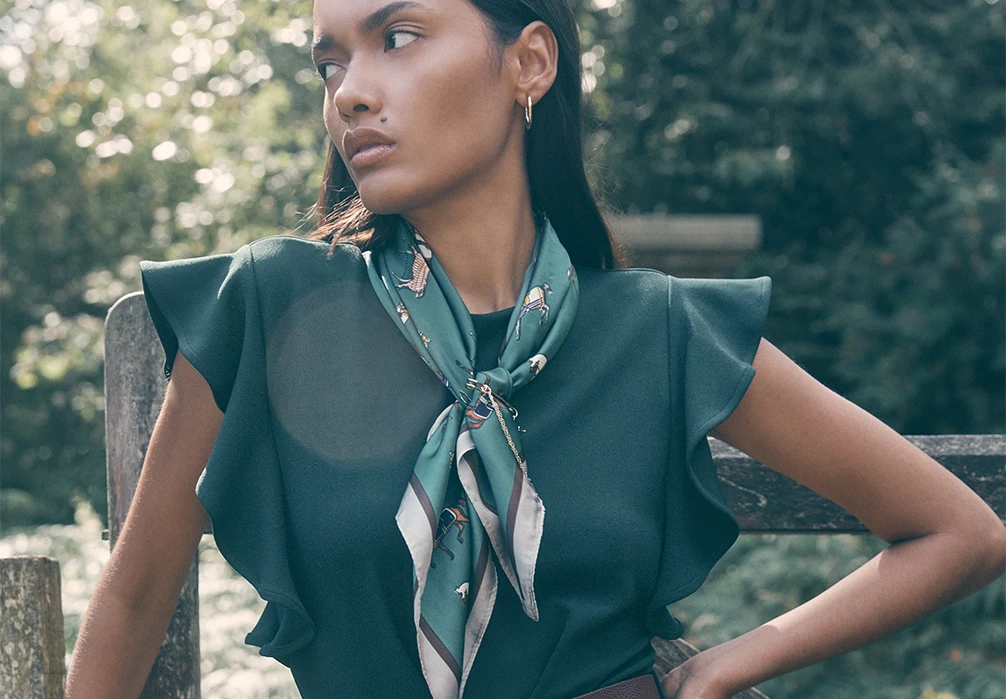 Model standing wearing a green satin scarf