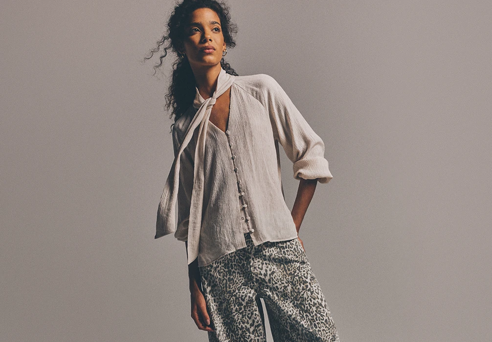 Model is wearing a white loose blouse and leopard print denim