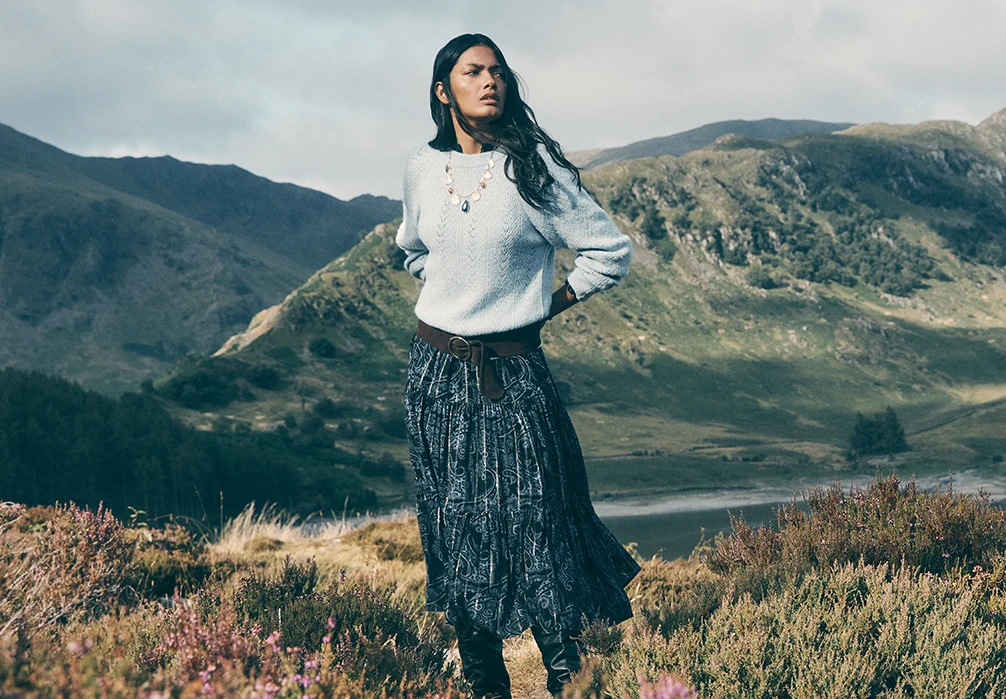 Model wearing a chevron shimmer blue knitted jumper and a paisley blue maxi dress