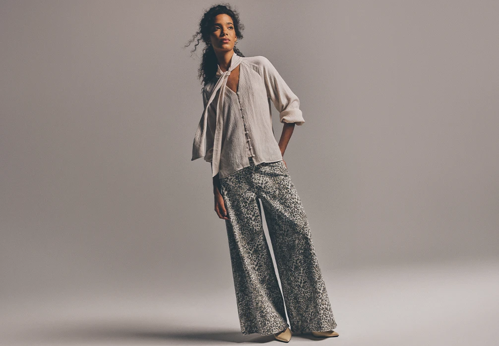 The model is wearing a white blouse with grey leopard print baggy jeans
