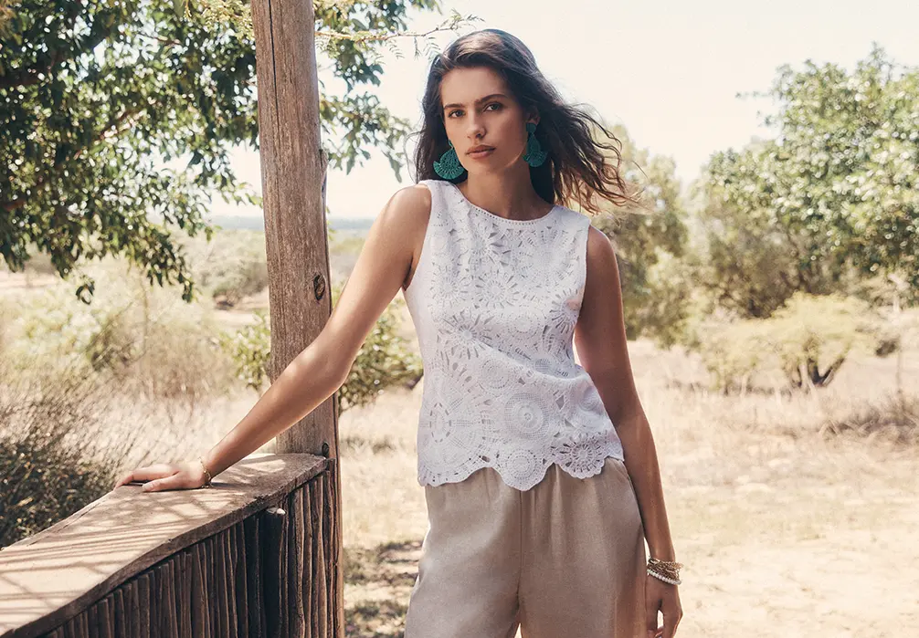 A girl standing in cotton crochet top. Text on image: Tap into this season's crochet trend with colourful tops, dresses and accessories.