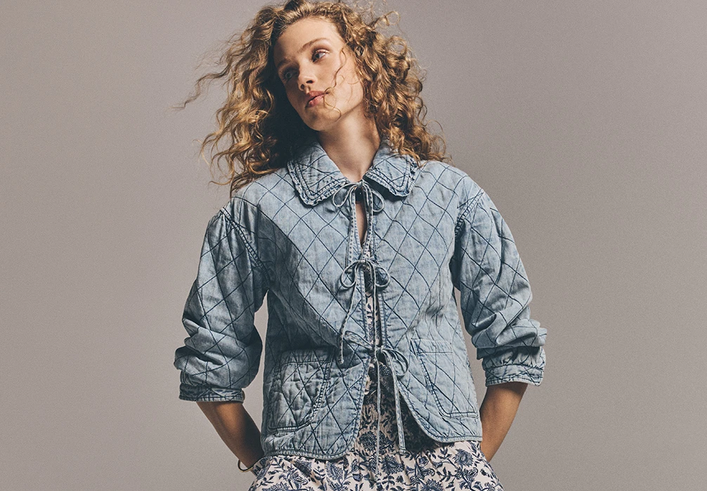 Model sitting on stairs wearing the Cotton Denim quilted jacket