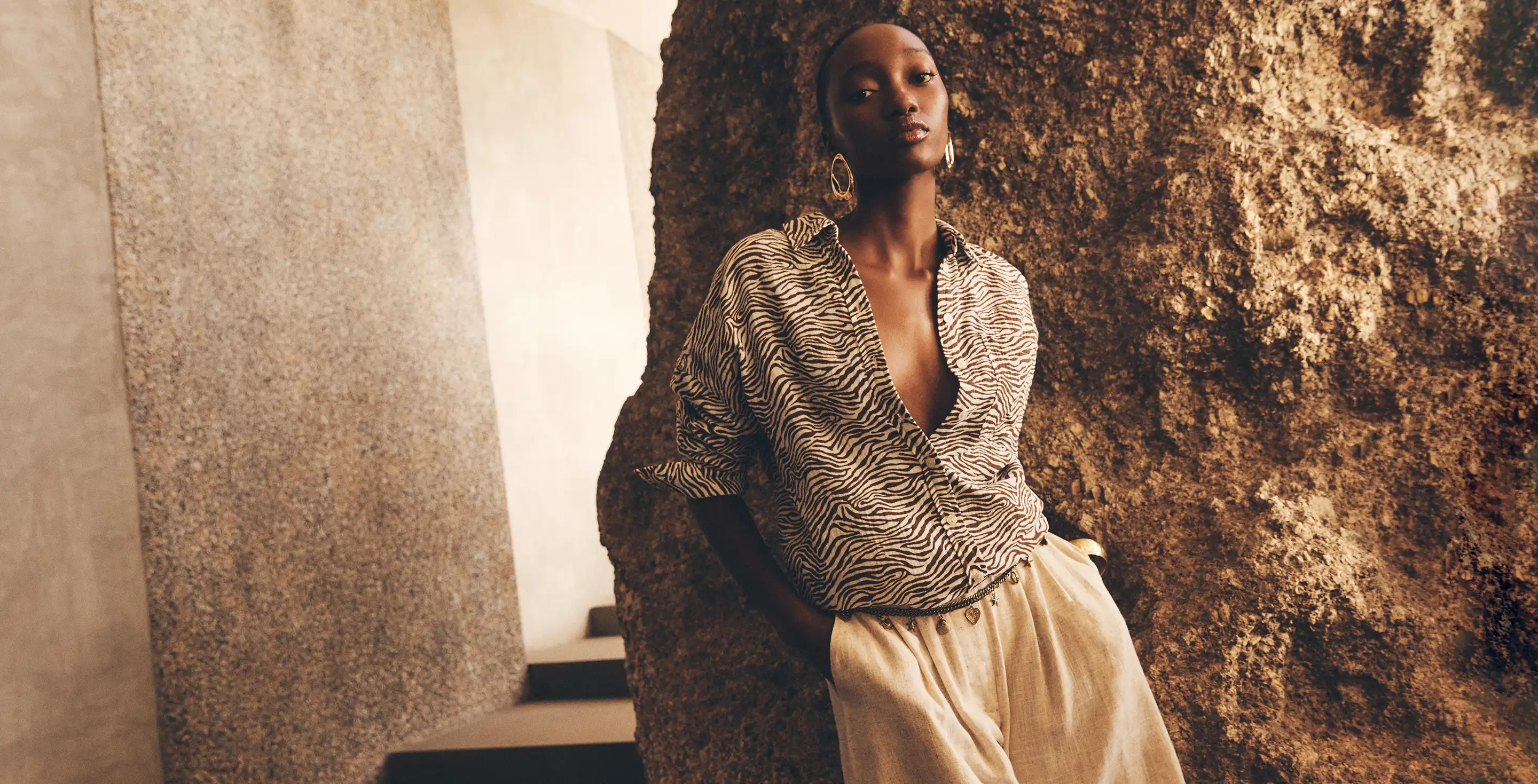 Model wearing a zebra print wrap shirt with gold wide-leg trousers