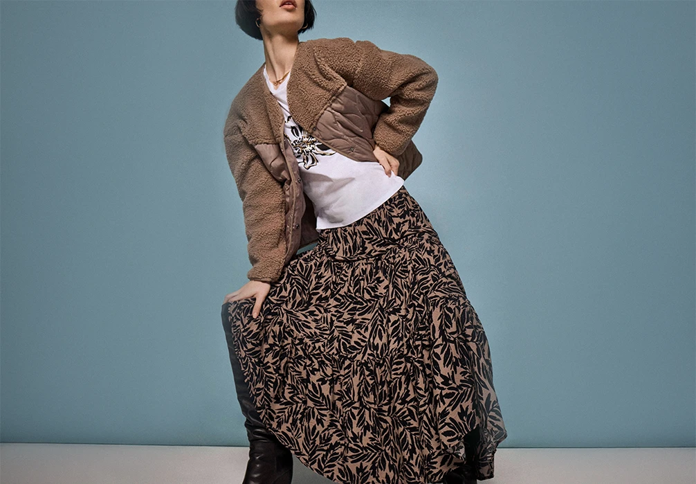 A girl standing in a waistcoat and skirt. Text on image: Explore our collection of new-in women’s skirts & shorts designed for every occasion. Whether you’re looking for a mini skirt, midi skirt, or maxi skirt, we have flattering styles that will take you from work to the weekend. Build your after-dark wardrobe with a chic leather skirt or black mini skirt. Get set for your next event with an elegant tulle skirt, velvet skirt, or sequin skirt. Elevate off-duty days with a timeless denim skirt, a knitted skirt, or a tiered maxi skirt. Discover printed mini shorts, suede shorts, & practical skorts that combine comfort & style. Shop new-in women’s skirts & shorts at Apricot now.