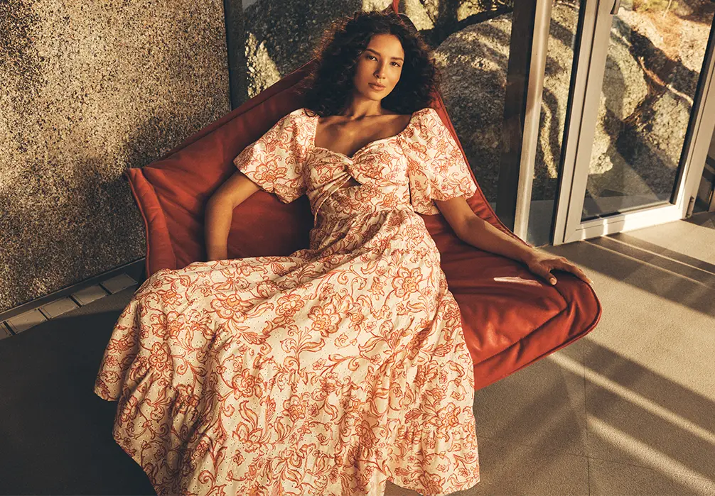 Model is wearing a parsley print dress while sitting